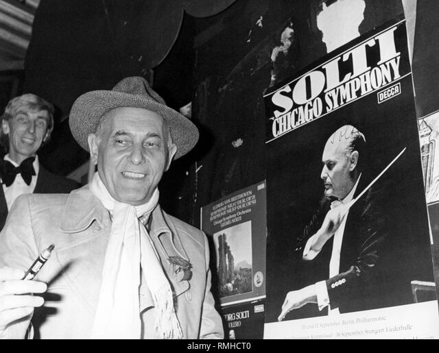 Sir georg solti conductor of the chicago symphony orchestra at an autograph session with a pen in his hand in the background a poster showing the musician conducting stock photo