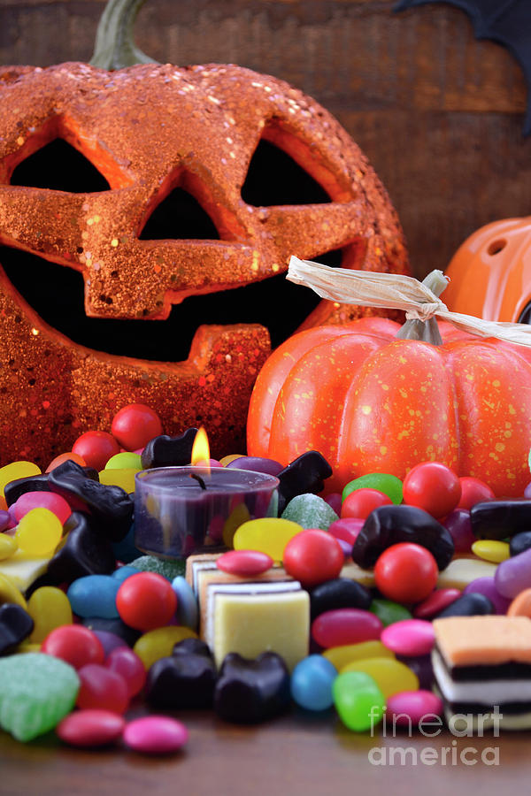 Halloween candy with pumpkins on dark wood background photograph by milleflore images