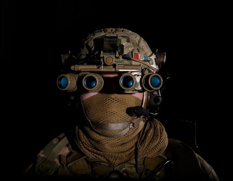 Soldier in military uniform with night vision goggles on background of dark wall photo