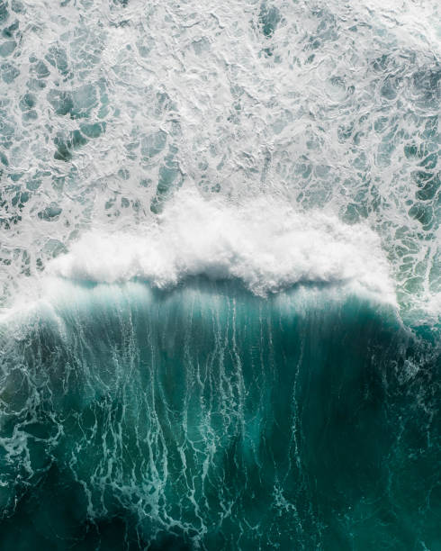 Beautiful aerial view of a wave crashing in a blue ocean during a storm stock photo