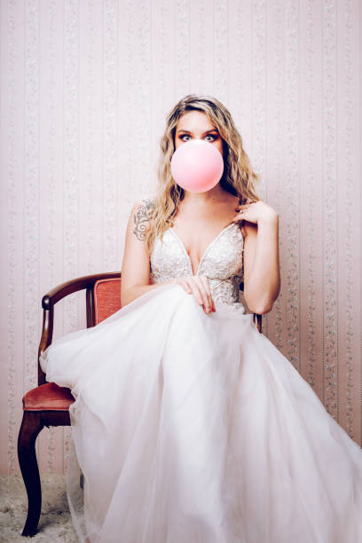 Beautiful bride with pink floral wallpaper and bubblegum stock photo