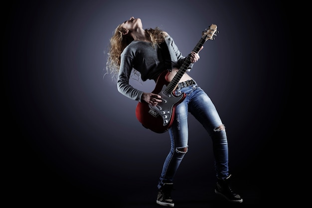 Premium photo young and beautiful rock girl playing the electric guitar