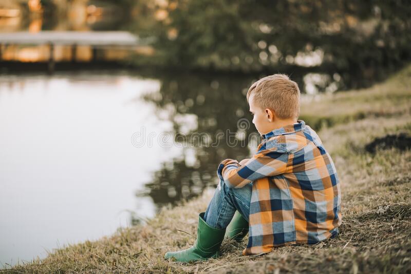 Sad boy sitting river stock photos
