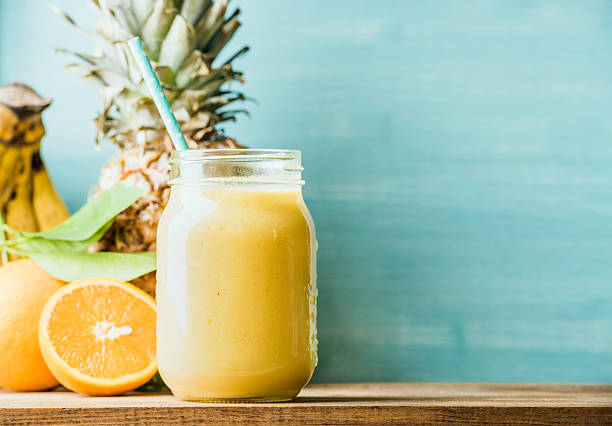 Freshly blended yellow and orange fruit smoothie in glass jar stock photo