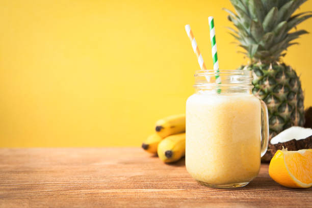 Fresh exotic smoothie with fruits and coconut milk on yellow background stock photo