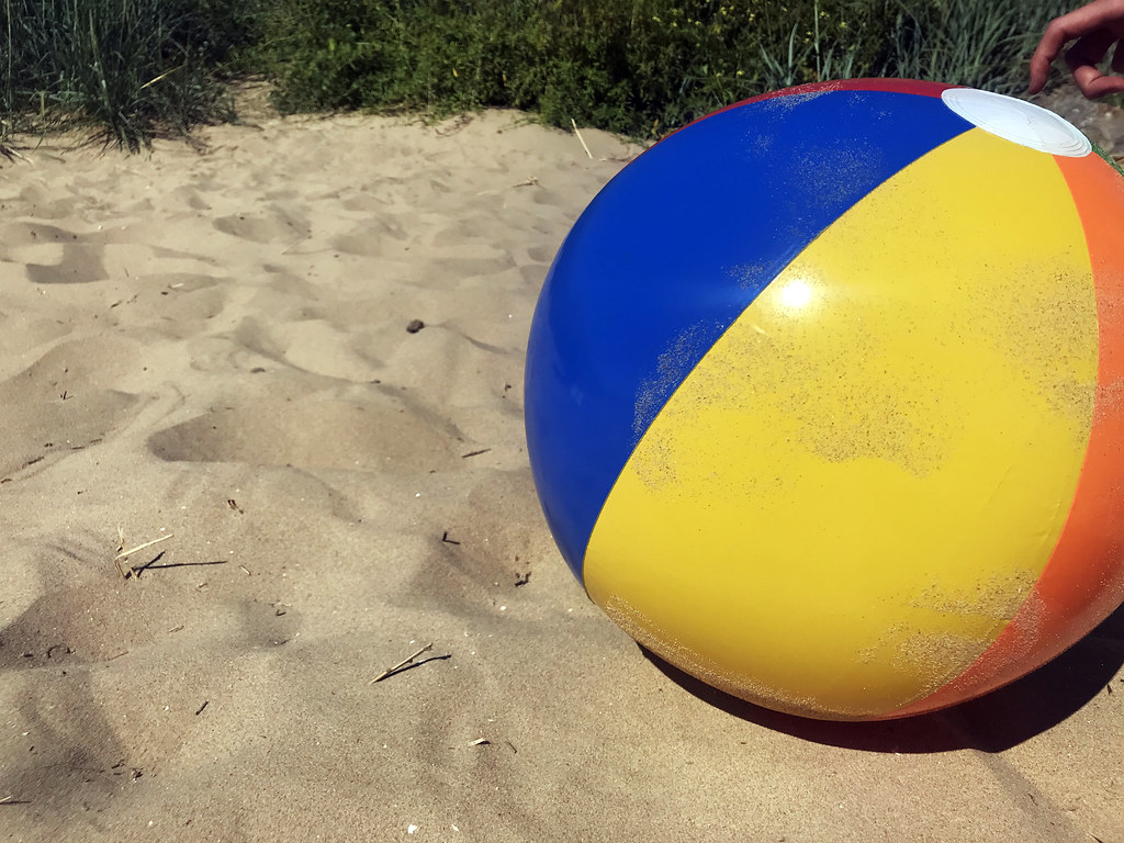 Coloured beach ball in the sand summer stock photo