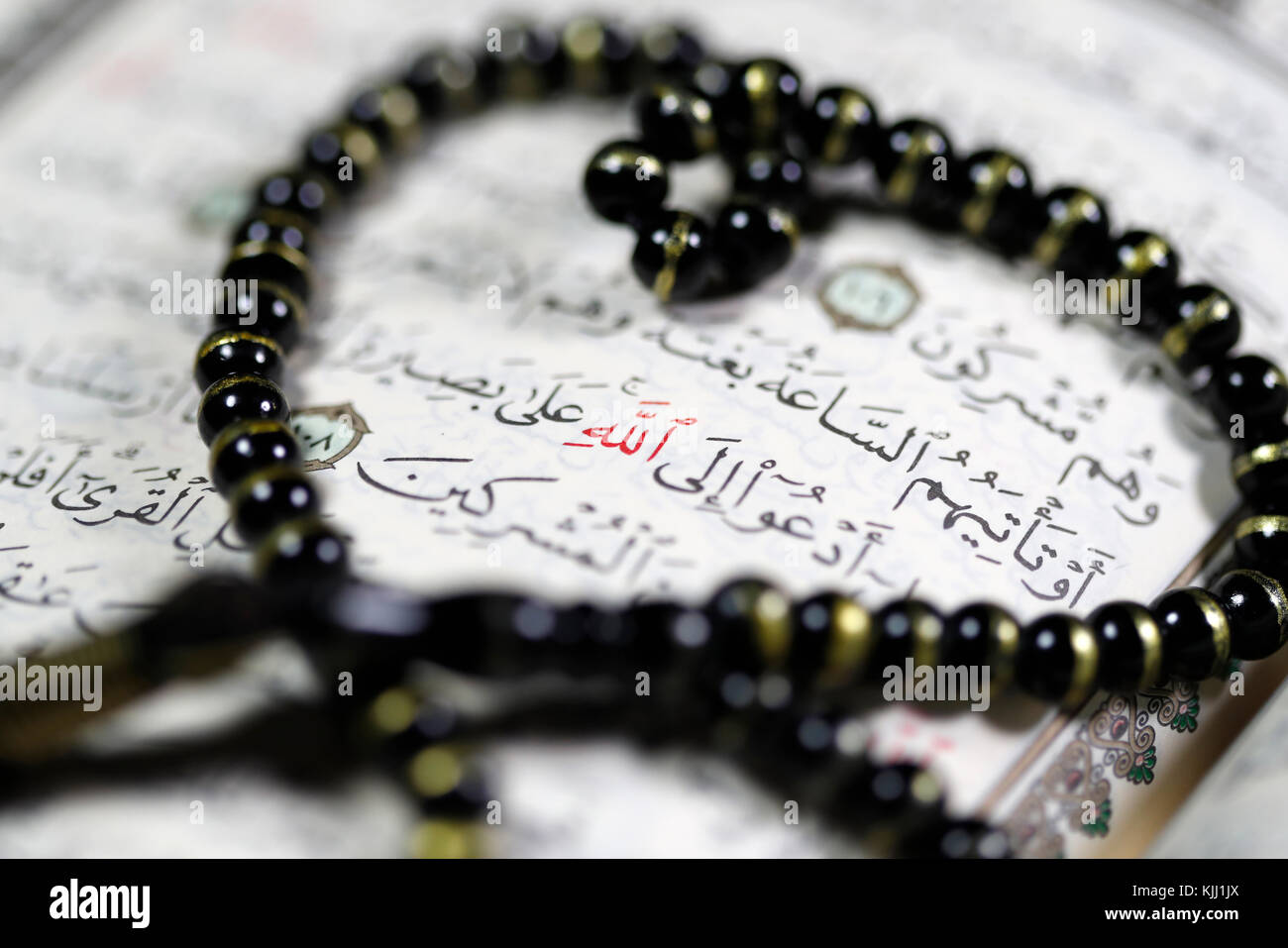 Quran and tasbih prayer beads allah monogram in red stock photo