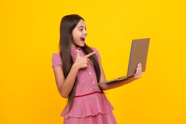 Premium photo amazed teen girl student school girl with laptop on isolated studio background video online webinar learn on laptop elearning lesson pc puter call excited expression