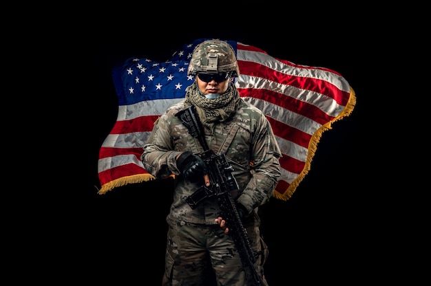 Premium photo photo of soldier holding the usa flag in background special force united states soldier or military contractors holding rifle image on background soldier army war weapon and technology concept