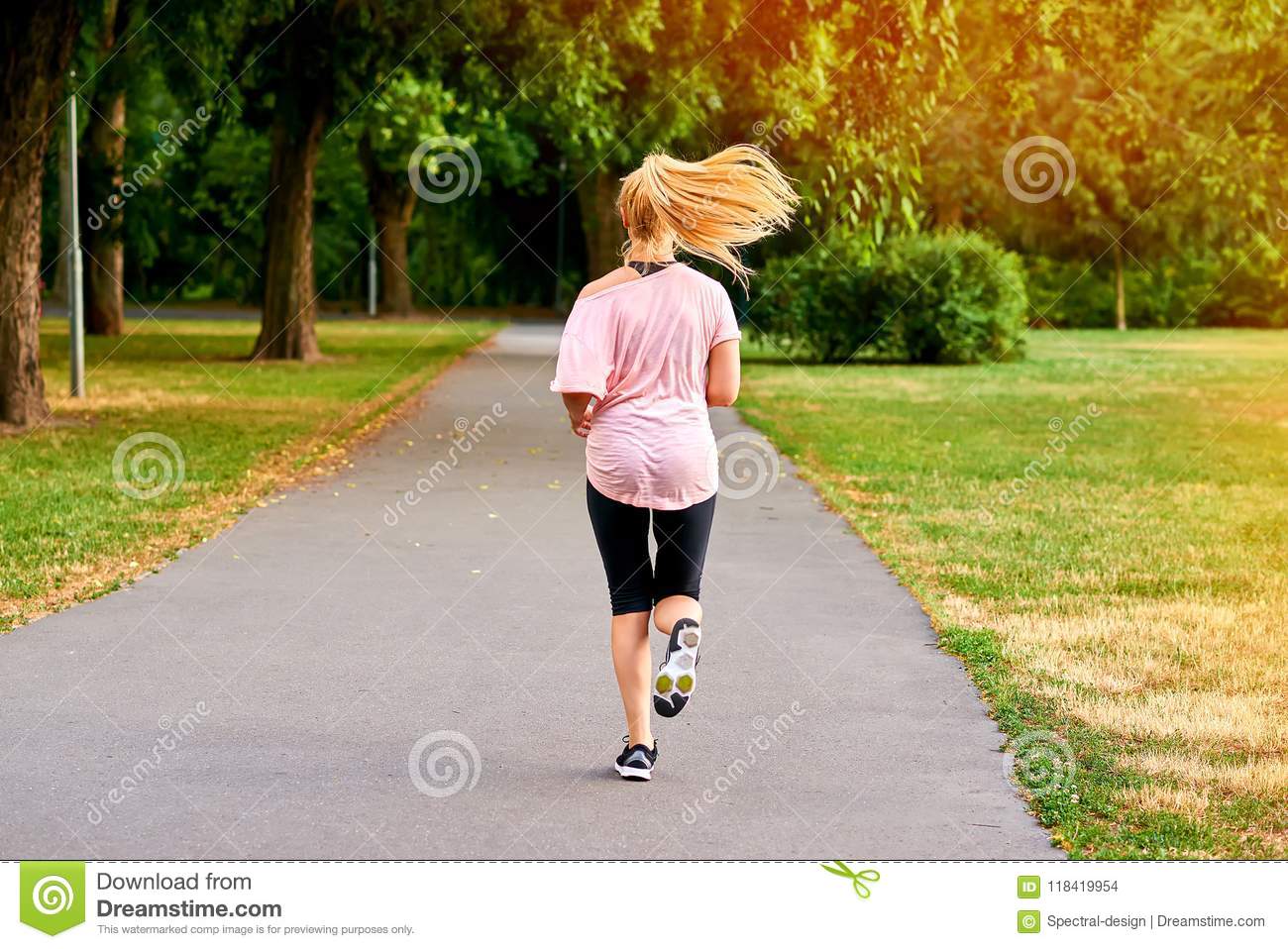 Young woman running away on the road in a park stock photo